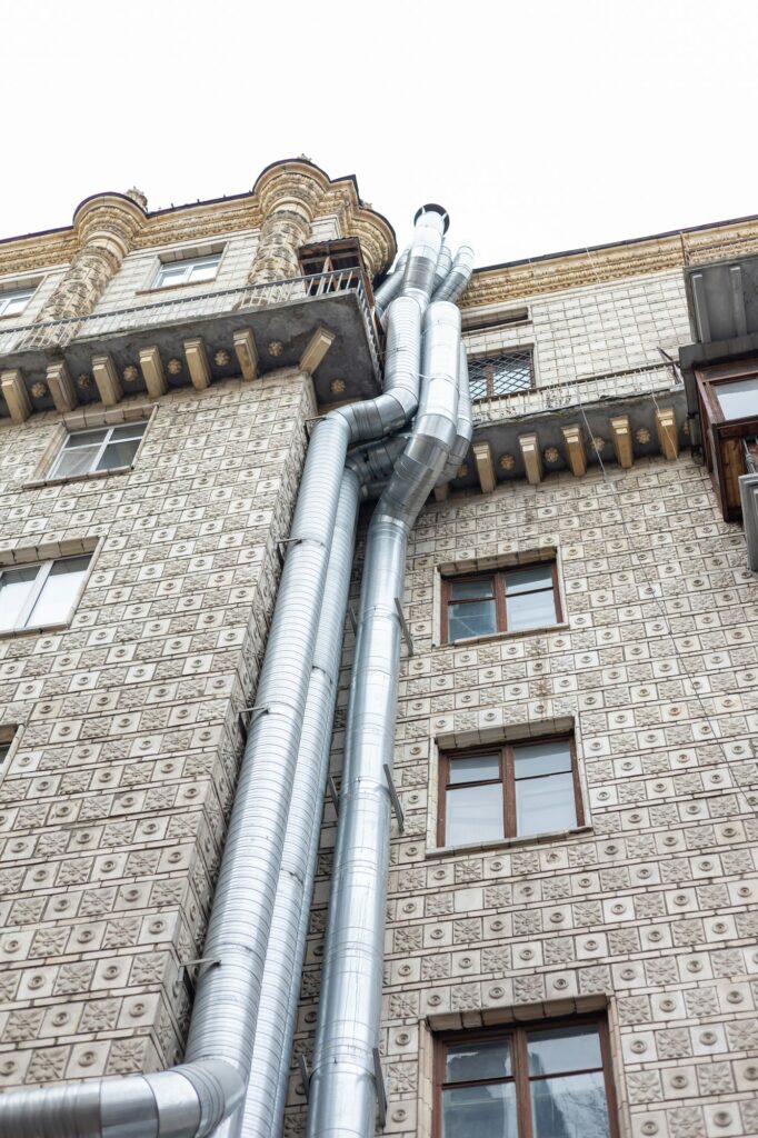 Gray metal fan pipe on buiding wall outside the buidling